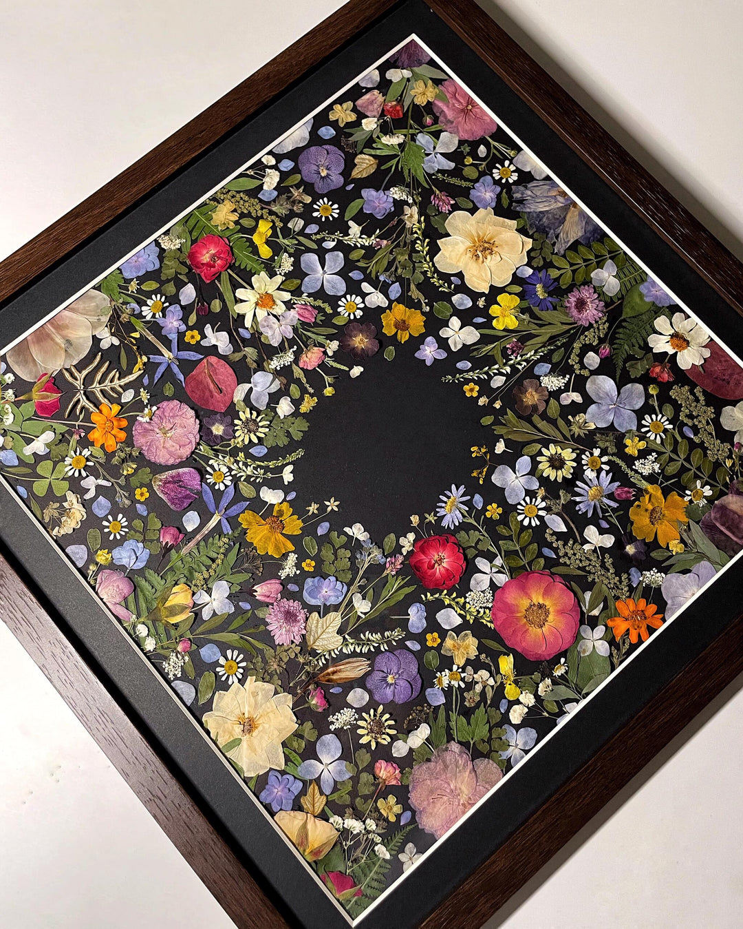 finished product of black background pressed flower frame art with flower petals 