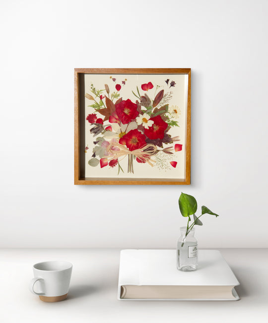 flower bouquet shaped red theme pressed flower frame art hanging above white desk
