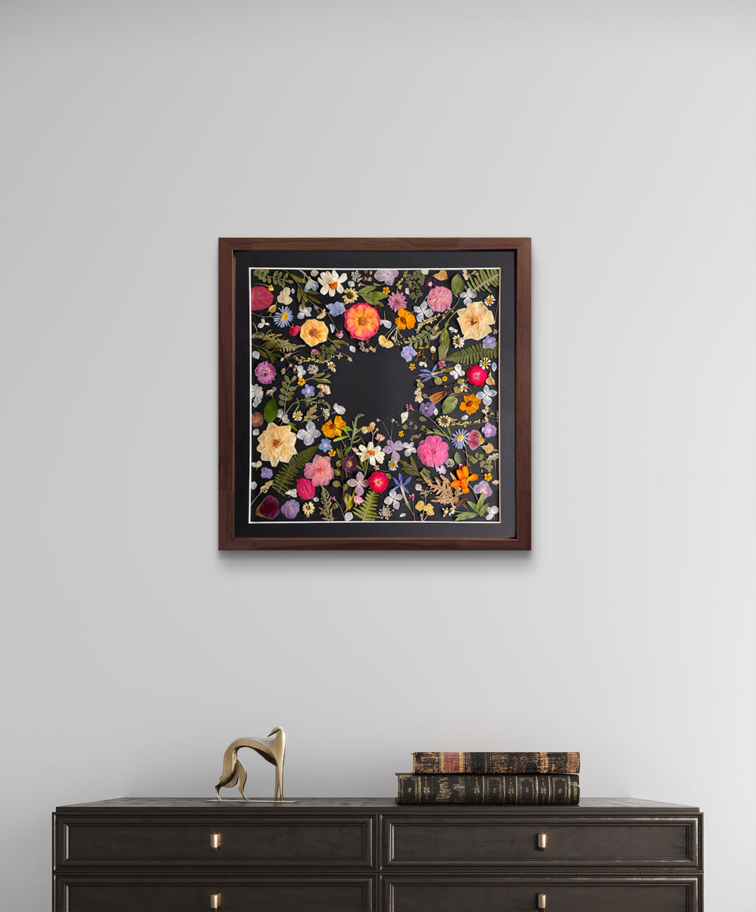 black background pressed flower frame art with flower petals hanging on the living room wall above black desk