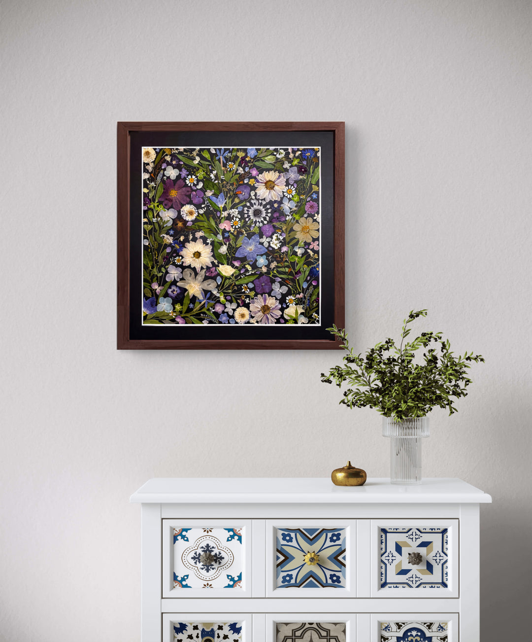 black background pressed flower frame art with flower petals hanging on the living room wall above white desk