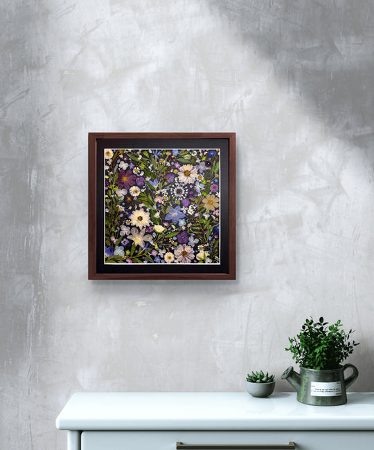 black background pressed flower frame art with flower petals hanging on the living room wall above white desk