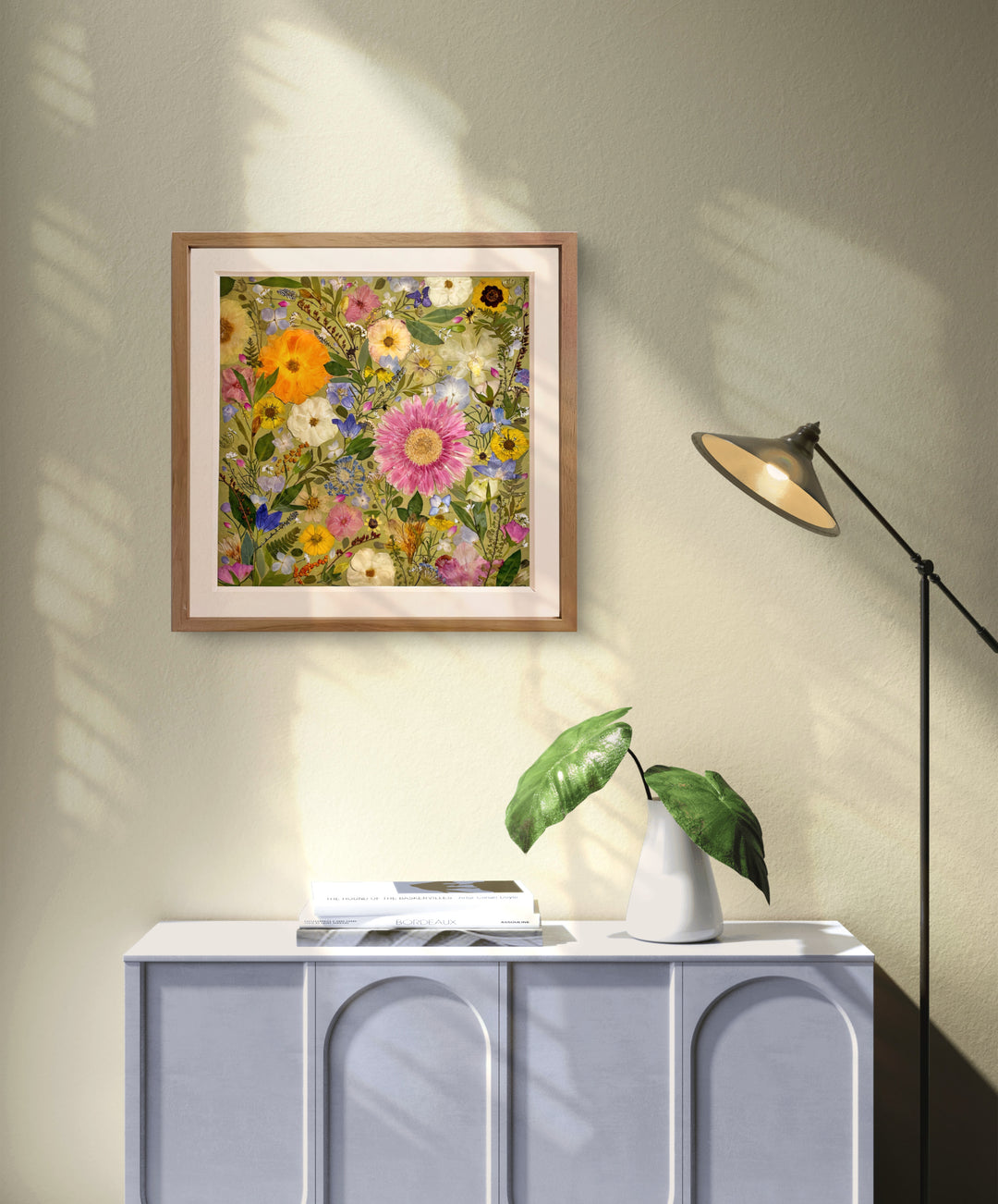 bright theme of pressed flower frame art that used different dried petals filled in every space of canvas hanging on the wall above purple desk