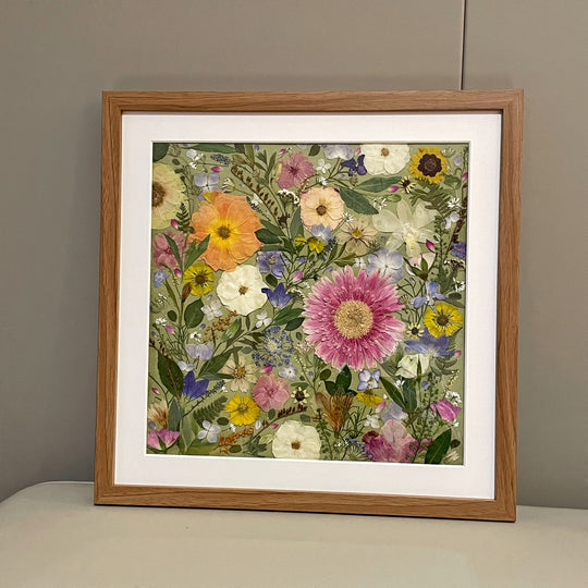 finished product of bright theme of pressed flower frame art that used different dried petals filled in every space of canvas.