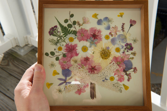 a hand is holding flower bouquet shaped pink theme pressed flower frame art