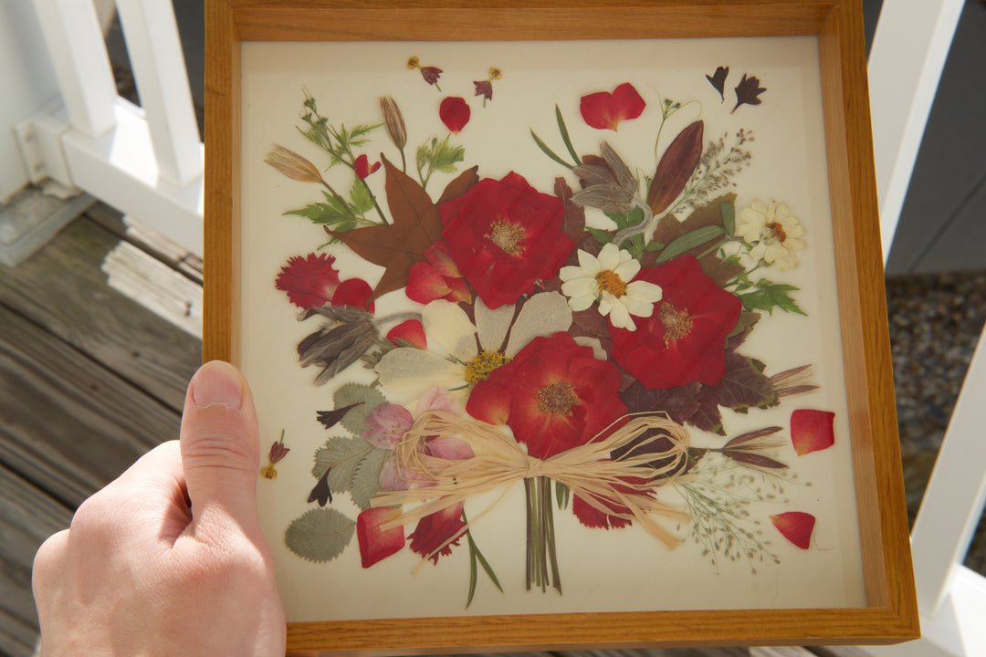 a hand is holding flower bouquet shaped red theme pressed flower frame art