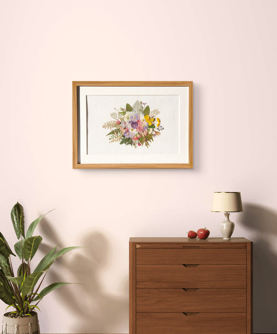 wreath shaped pressed flower frame art hanging above wood dresser 